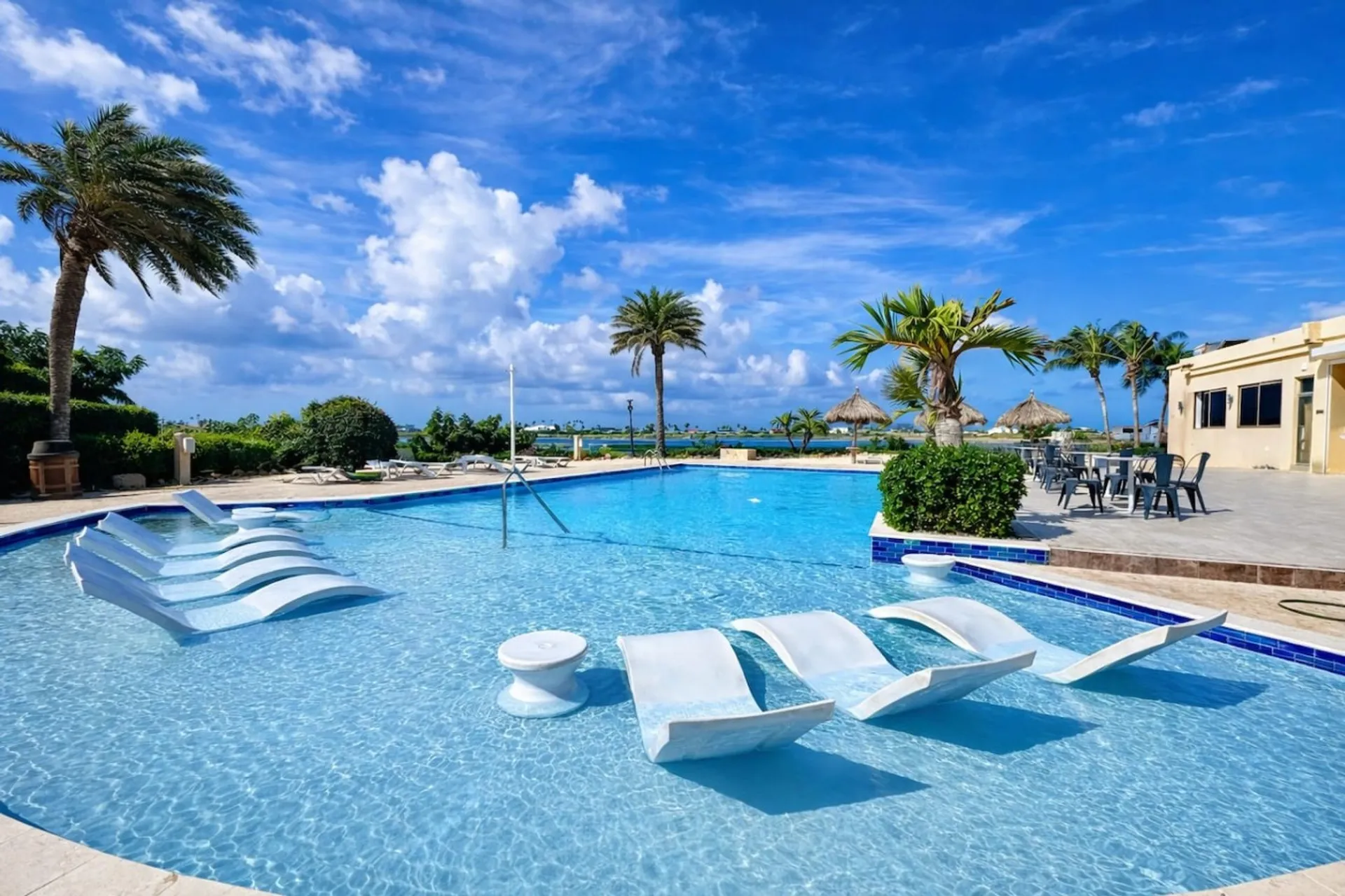 Shared clubhouse pool at Gold Coast Aruba, with loungers and palm trees